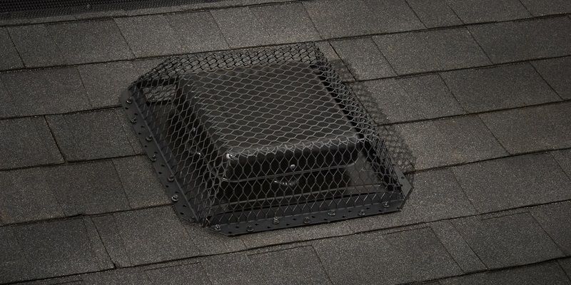 A black galvanized HY-GUARD EXCLUSION Roof VentGuard installed over a static roof vent on a roof with black shingles.