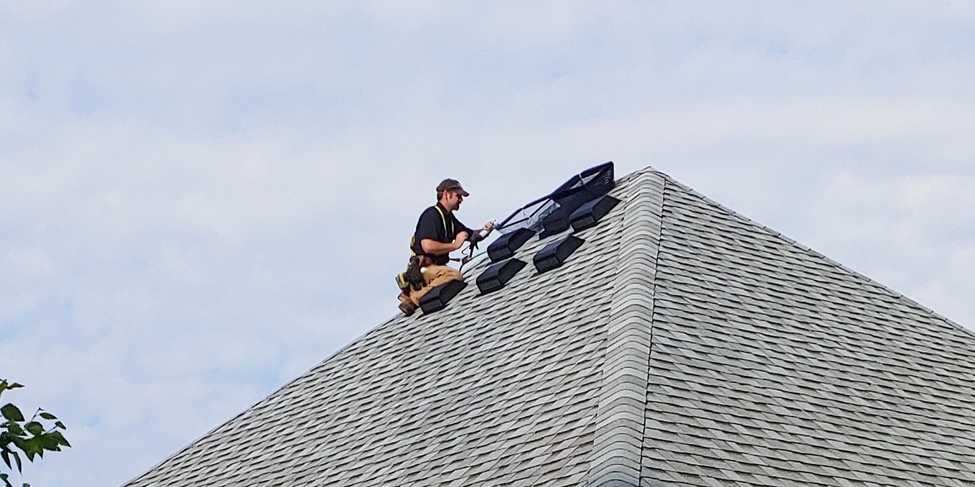 A man on a roof installing HY-GUARD EXCLUSION Roof Vent guards over box vents.