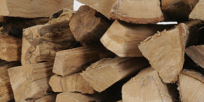 A close-up of a pile of cord wood. About a dozen split logs are visible.
