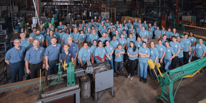 All the HY-C employees wearing matching t-shirts posing for a picture on the HY-C factory floor.