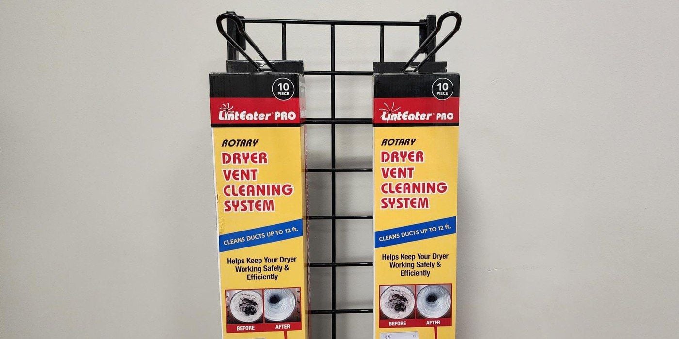 Two LintEater Pro dryer vent cleaning kits hanging on a wire display rack against a drywall wall.