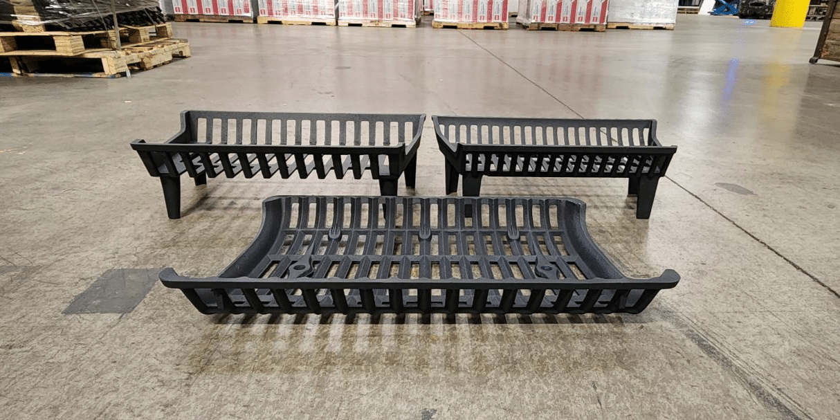 Three Liberty Foundry Co. cast iron fireplace grates laid out on a concrete factory floor.