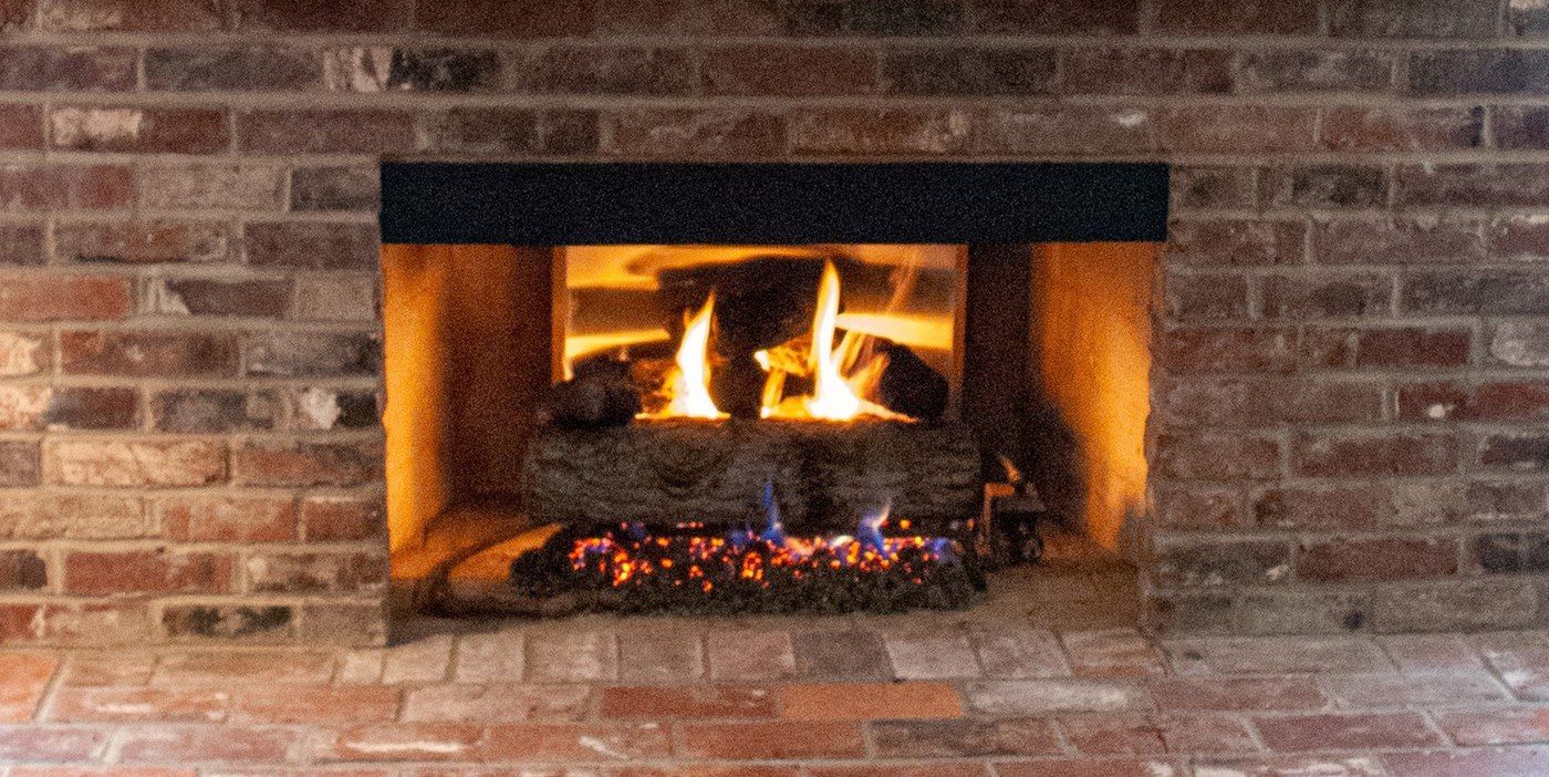 A smoke guard installed on a brick fireplace above a firebox with a roaring fire inside.