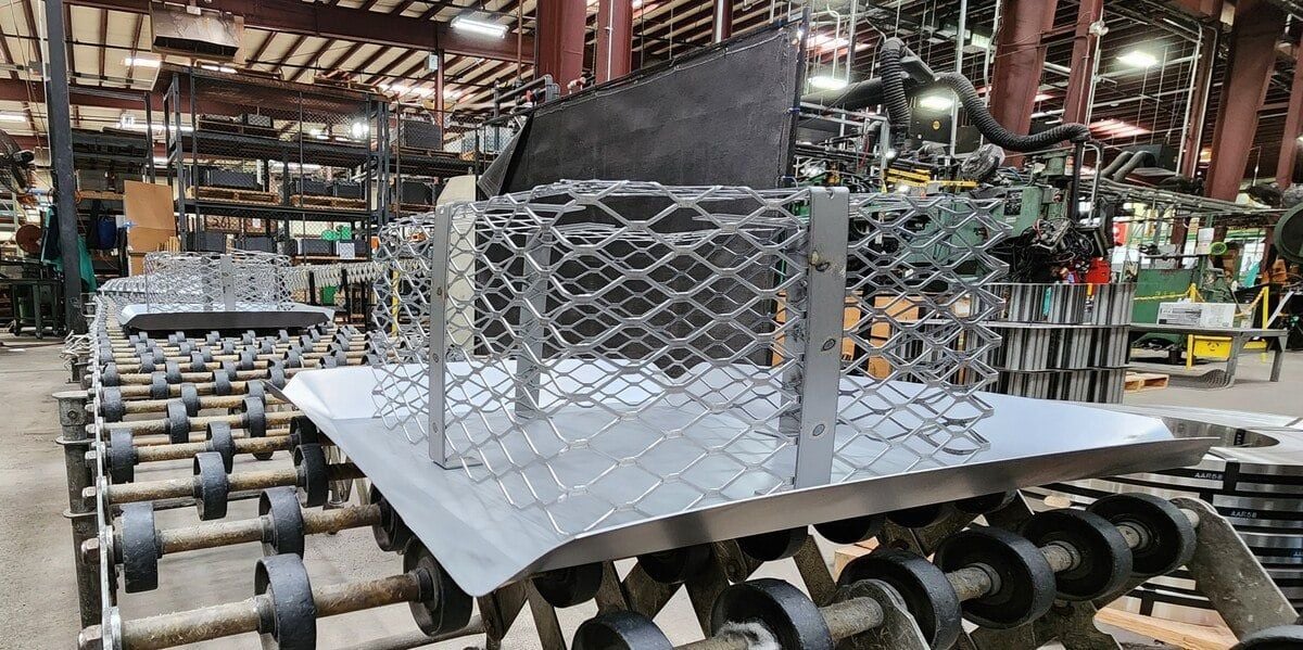 A galvanized steel multi-fit chimney cap on a factory conveyor belt on the HY-C chimney cap production line.