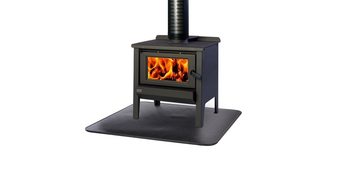 A wood stove with a fire burning in the firebox sitting on top of a black HY-C stove board against a white background.